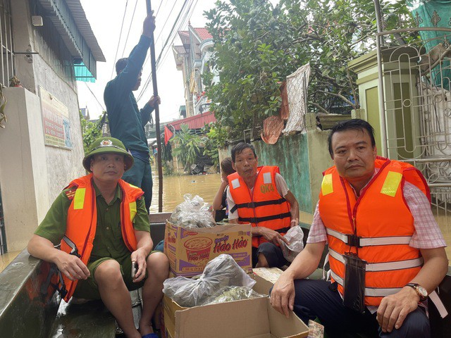 Lực lượng chức năng phường Hàm Rồng đưa hàng cứu trợ vào khu ngập lụt.