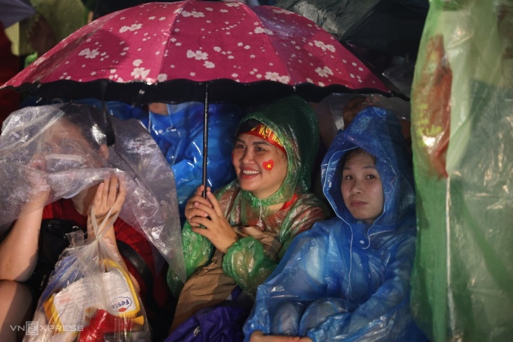 Nhiệt độ ngoài trời 26 độ C, người phụ nữ cười tươi rói dưới mưa. Ảnh: Quỳnh Trần