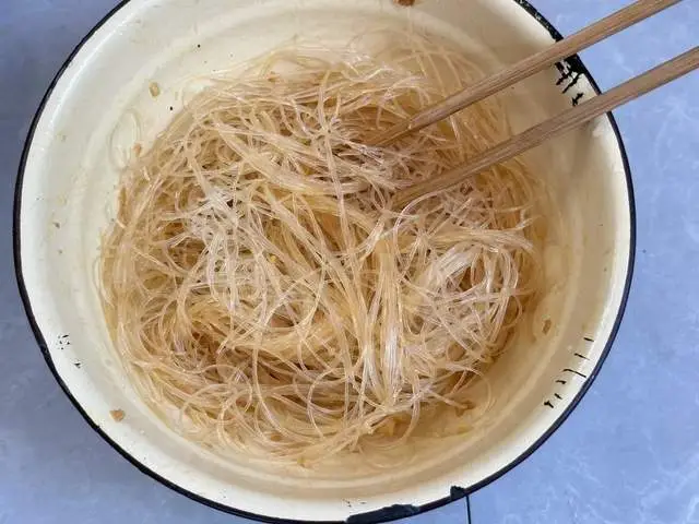 Miến ngâm mềm, xếp xuống đáy đĩa, chan một thìa sốt tỏi phi rồi trộn đều.