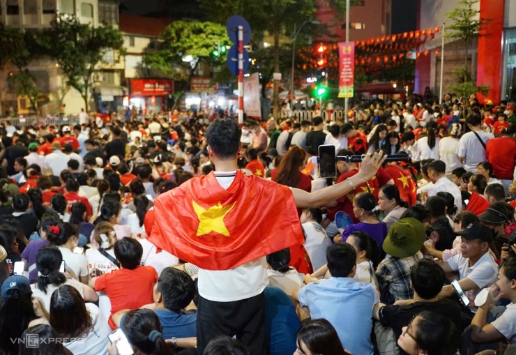 Một người dân khoác cờ Tổ quốc, ghi lại khoảnh khắc đứng giữa dòng người trên phố đợi đoàn diễu binh. Ảnh: Phạm Dự