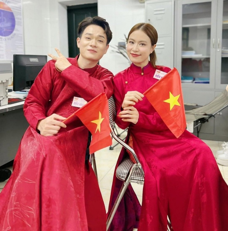 Hoàng Thùy Linh và đồng nghiệp diện áo dài đỏ rực, mang cờ nước chuẩn bị bước vào đội hình tổng duyệt.