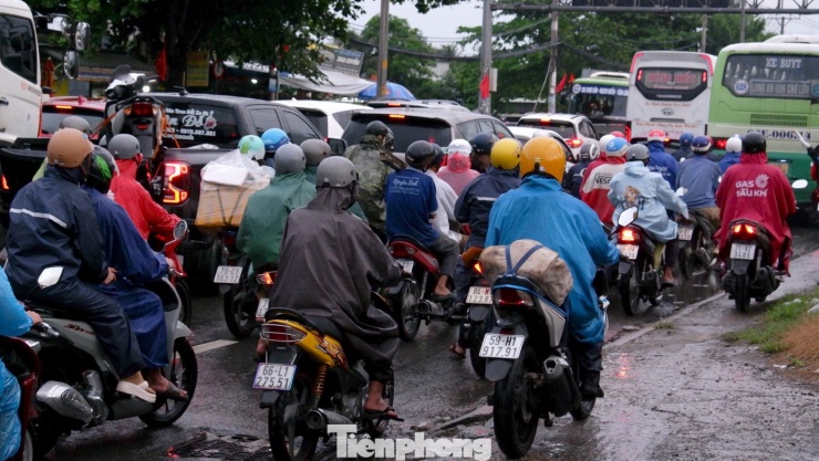 Người dân che chắn bằng áo mưa, vali chất chồng phía sau xe máy, kiên nhẫn vượt qua đoạn kẹt xe để kịp về quê đoàn tụ cùng gia đình.