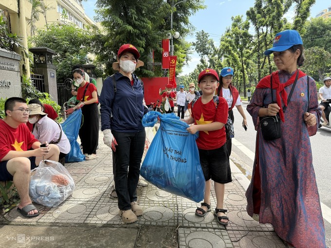 Chị Thu Hoài và con trai Mạnh Đức nhặt rác trên đường Kim Mã, sáng 30/8. Ảnh: Quỳnh Nguyễn