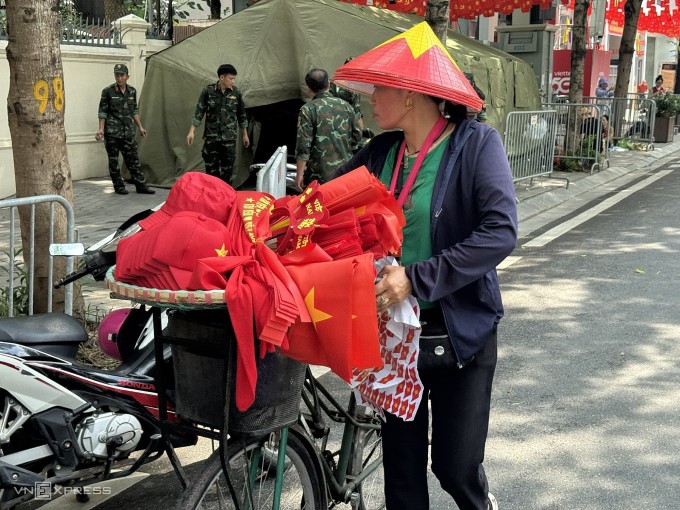 Một người bán hàng rong mũ, quạt, nón cờ đỏ sao vàng trên phố Điện Biên, sáng 29/8. Ảnh: Nga Thanh