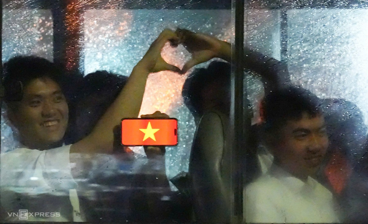 Chiến sĩ cùng đồng đội tạo hình trái tim bằng tay vừa giơ hình nền điện thoại cờ đỏ sao vàng qua cửa kính. Ảnh: Tùng Đinh