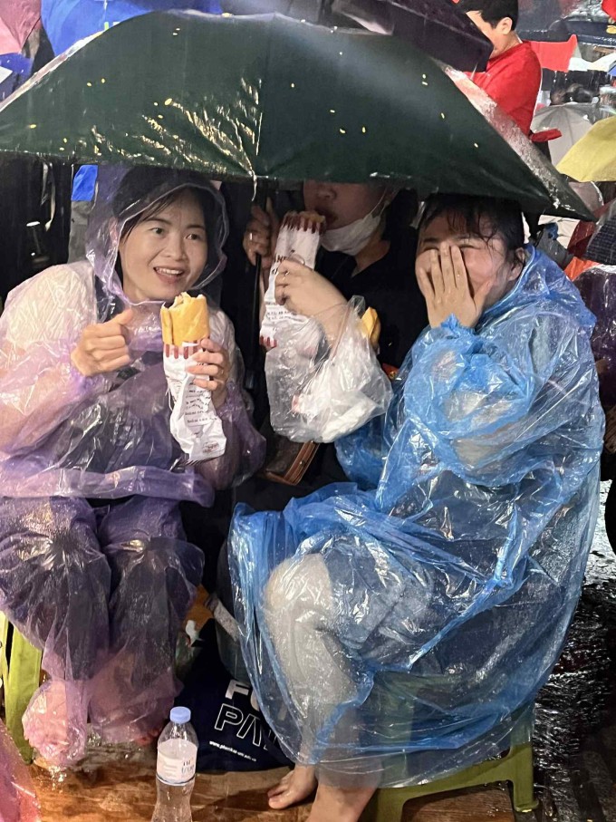 Người nhà chị Thùy Trang ngồi trú mưa khi chờ duyệt binh, sau khi được chị giữ chỗ, tối 29/8. Ảnh nhân vật cung cấp