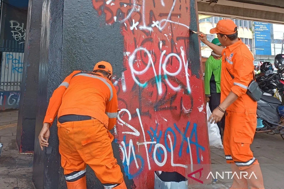 Lao công sơn lại bức tường bị người biểu tình vẽ bậy (ảnh: Antara News)