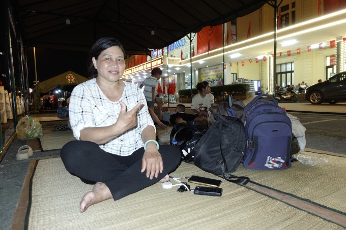 Bà Hường trông balo cho hai thành viên khác trong gia đình trước cửa ga Hà Nội. Ảnh: Tú Nguyễn