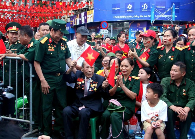 Ông Bình (ngồi hàng nhất cầm cờ) ngồi vị trí ưu tiên dành cho cựu chiến binh xem tổng duyệt diễu binh, hôm 31/8. Ảnh gia đình cung cấp