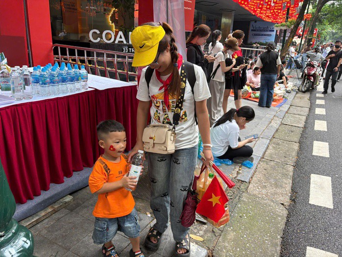 Bé trai cùng mẹ đi xem diễu binh, diễu hành A80 được hỗ trợ nước uống