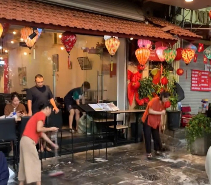 Hình ảnh nhân viên quán ăn trên phố Hàng Khay đổ nước xà phòng rửa vỉa hè lúc người dân trải bạt ngồi chờ xem diễu binh gây phản cảm. Ảnh cắt từ clip