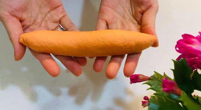 Lấy viên bột đã vo tròn theo thứ tự trước đến sau. Cán bột dài ra trên nhỏ dưới to, quấn từ trên đầu nhỏ xuống đầu to, bấm mép cho liền. Dùng hai tay để hình chữ V lăn bánh từ trên xuống. Tạo thành hình bánh mì.