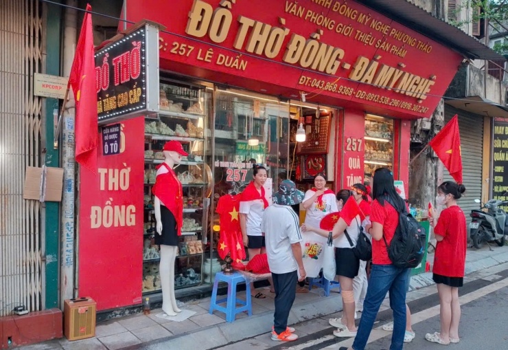 Một cửa hàng bán đồ thờ trở thành điểm bán cờ Tổ quốc, áo in hình cờ Tổ quốc và đồ uống.
