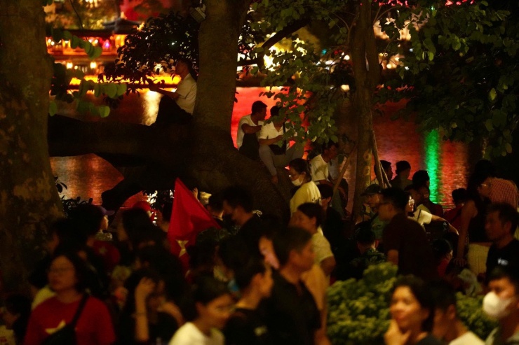 Người dân leo cây, chen chân tìm chỗ xem pháo hoa dọc hồ Gươm.