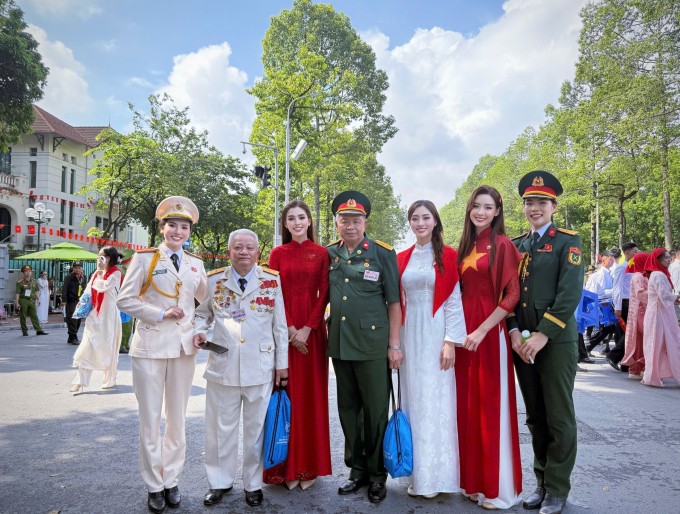 Hoa hậu Tiểu Vy, Lương Thùy Linh, Bảo Ngọc (diện áo dài, từ trái sang) chụp ảnh cùng các chiến sĩ trên phố khi tham gia lễ diễu hành mừng đại lễ 2/9. Ảnh: Nhân vật cung cấp
