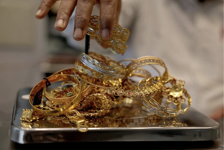 Một thợ kim hoàn đang cân trang sức vàng bên trong showroom ở Ahmedabad, Ấn Độ. Ảnh: REUTERS