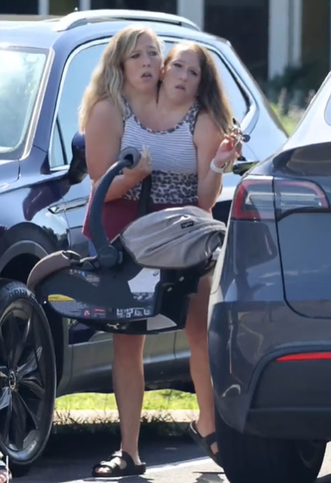 Abby và Brittany xách nôi em bé. Ảnh chụp màn hình