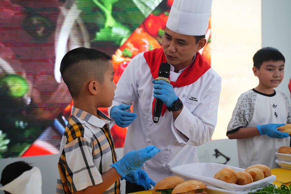 &nbsp;Chef tận tình hướng dẫn bé làm bánh mỳ. (Ảnh: VNA).