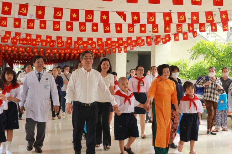 Lãnh đạo TP, lãnh đạo bệnh viện, cô giáo cùng phụ huynh đưa các bệnh nhi vào lớp học. Ảnh: DI LINH