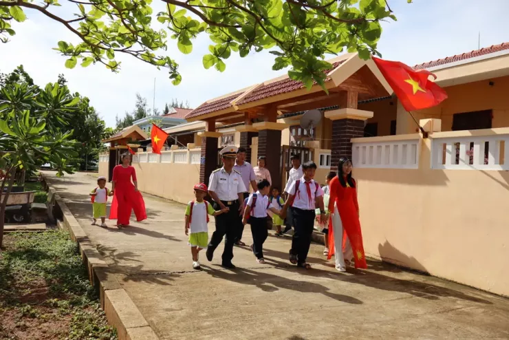 Các em nhỏ cùng bố mẹ, cán bộ chiến sĩ trên đảo Đá Tây tung tăng tới trường dự lễ khai giảng. Ảnh: NA