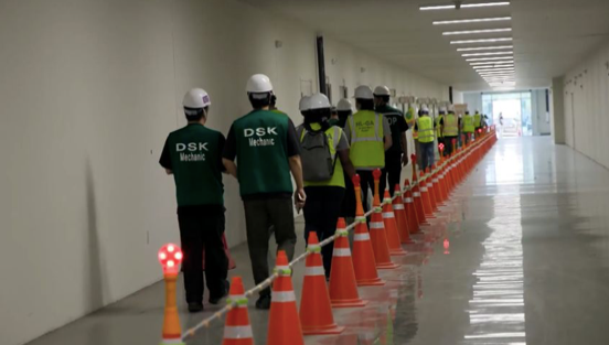 Các công nhân trong nhà máy xếp hàng theo yêu cầu của lực lượng trấn áp nhập cư. (Ảnh: CNN)