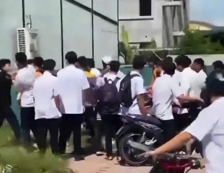 Nhóm học sinh áo trắng hành hung bạn học trước cổng trường. Ảnh cắt từ clip.