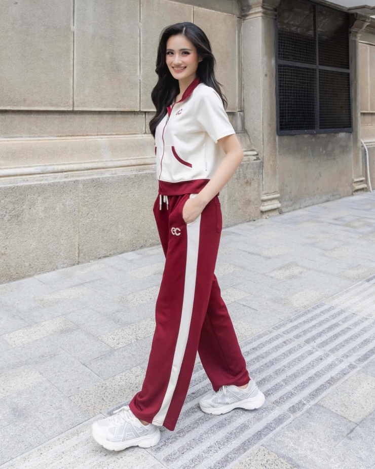 Ý Nhi diện phong cách thể thao với bộ tracksuit kết hợp sneakers trắng. Trang phục mang sắc đỏ nâu rượu và kem lấy cảm hứng từ đồ tập những năm 1980.