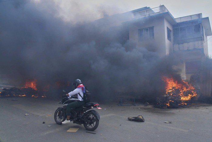 Một người đi xe máy qua đồn cảnh sát đang bốc cháy ở Kathmandu ngày 9-9. Ảnh: AP