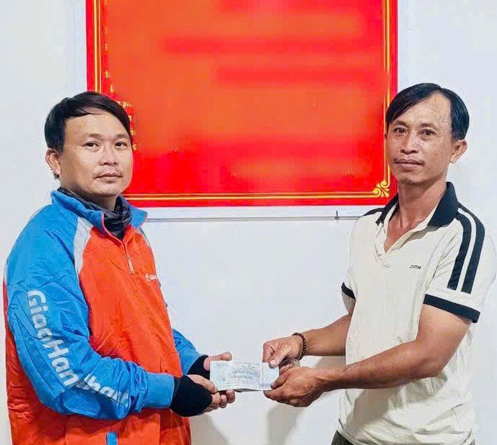 Ông Đinh Công Bình (phải) trao lại số tiền nhặt được cho ông Nguyễn Công Lập tại trụ sở công an.