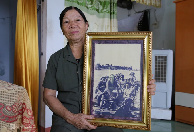 Bà Thu cùng bức ảnh do nhà báo Đoàn Công Tính chụp cha con bà lái thuyền đưa bộ đội qua sông Thạch Hãn năm 1972. Ảnh: Đắc Thành