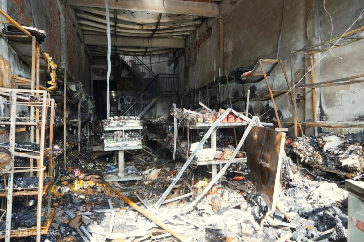 Toàn bộ tài sản trong tiệm tạp hoá bị lửa thiêu rụi. Tường, trần và dãy kệ kê hàng sập, hư hỏng. Chủ hộ chỉ kịp lấy giấy tờ.