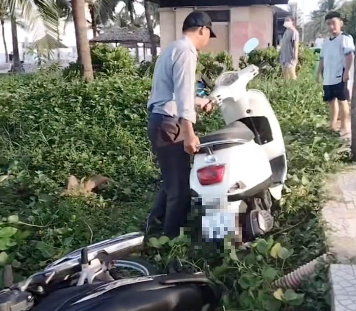 Nam nhân viên thuộc Đội Quản lý trật tự du lịch biển – Ban Quản lý bán đảo Sơn Trà và các bãi biển du lịch Đà Nẵng dắt xe máy của du khách từ vỉa hè xuống bãi cát. Ảnh cắt từ clip