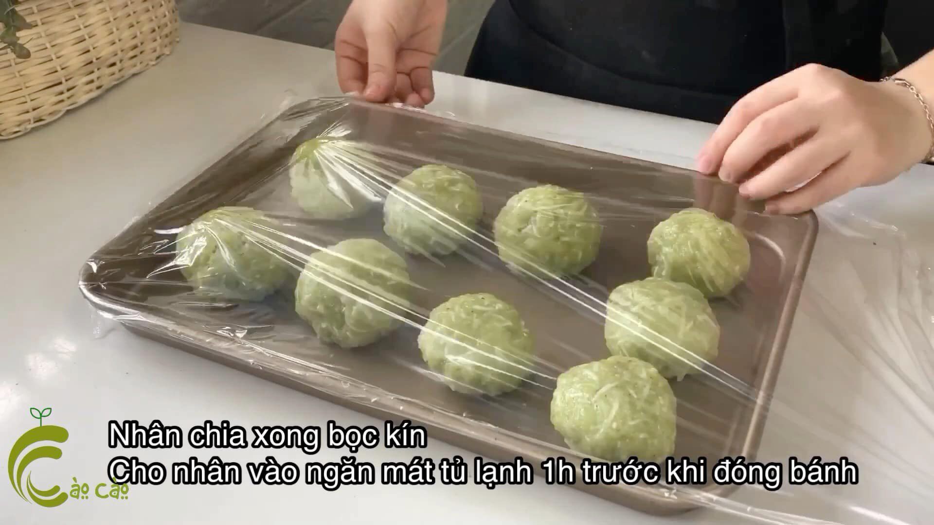 Để nhân cốm nguội bớt, chia cốm xào thành từng viên 90g. Dùng màng bọc thực phẩm bọc kín khay nhân để cốm không bị khô mặt rồi cho vào tủ lạnh khoảng 30-60 phút trước khi đóng bánh.