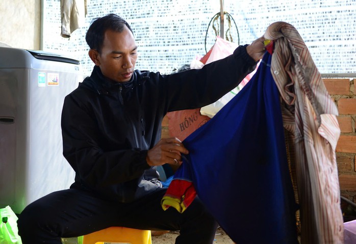 Anh Lơ Mu Ha Khen cầm bộ quần áo của ông Lơ Mu Ha Khen mang trong 6 ngày lạc trong rừng.