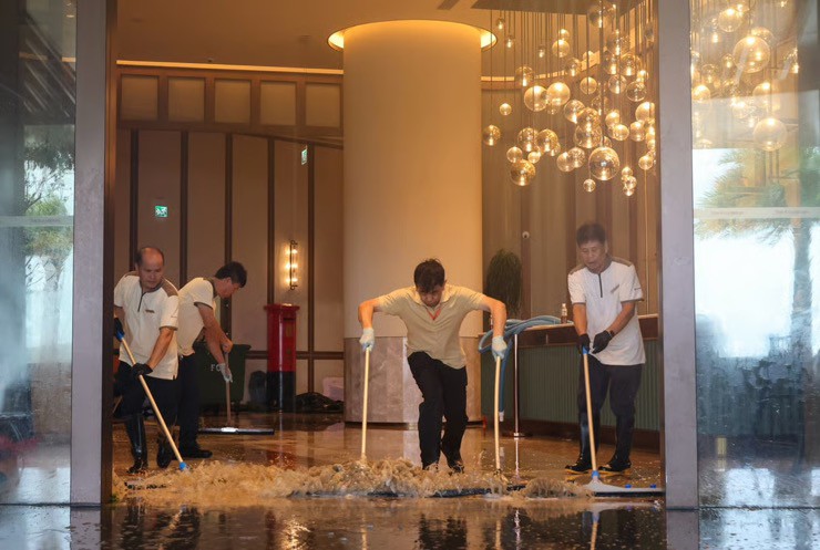 Nhân viên khách sạn lau dọn tiền sảnh sau khi sóng biển ập vào. Ảnh: SCMP.