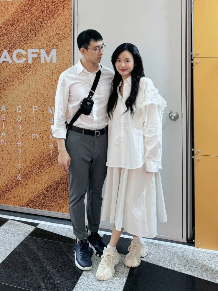 Cặp vợ chồng son mặc sơ mi trắng đồng điệu khi tham gia hoạt động thuộc khuôn khổ Busan International Film Festival 2025. Midu ưu tiên phom áo suông giấu đường cong, tạo nên hình ảnh trẻ trung.