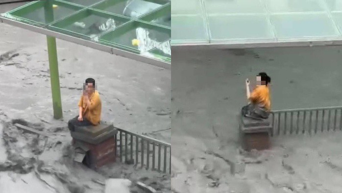 Người phụ nữ ngồi cô độc và ướt sũng trên trụ cổng giữa dòng lũ. Ảnh: Đài truyền hình Dân chủ Đài Loan