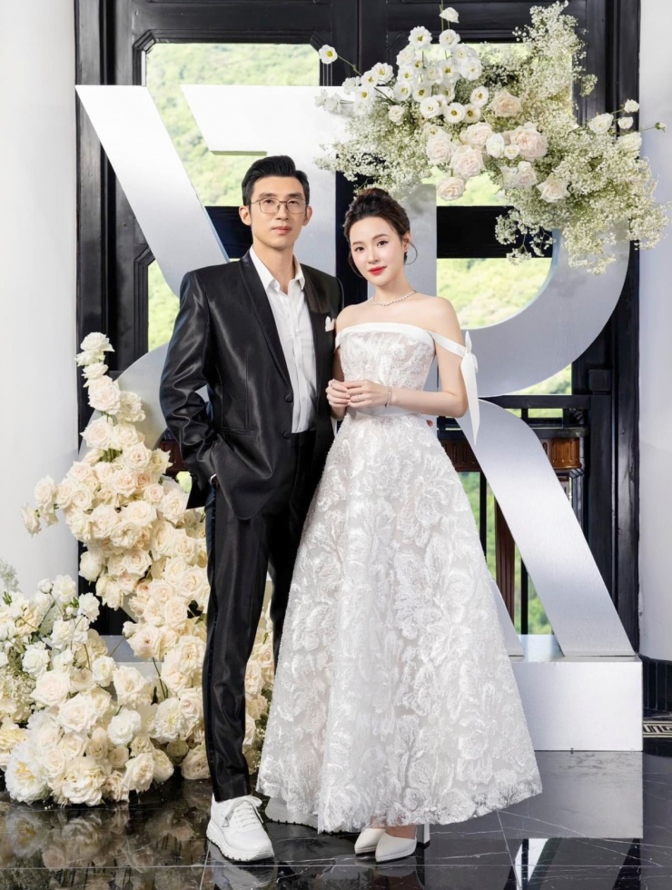 Tại show váy cưới của Chung Thanh Phong ở Đà Nẵng, Midu tôn dáng với đầm ren trễ vai. Chồng cô tạo vẻ hiện đại bằng giày thể thao của Prada với bộ suit bóng.