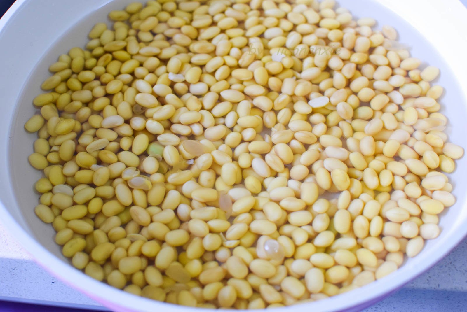 400g đậu nành ngâm trong nước sạch cho nở căng hạt. Mùa lạnh cần ngâm 10 tiếng trở lên,&nbsp;mùa nóng&nbsp;thì nên thay nước thường xuyên để tránh bị chua.