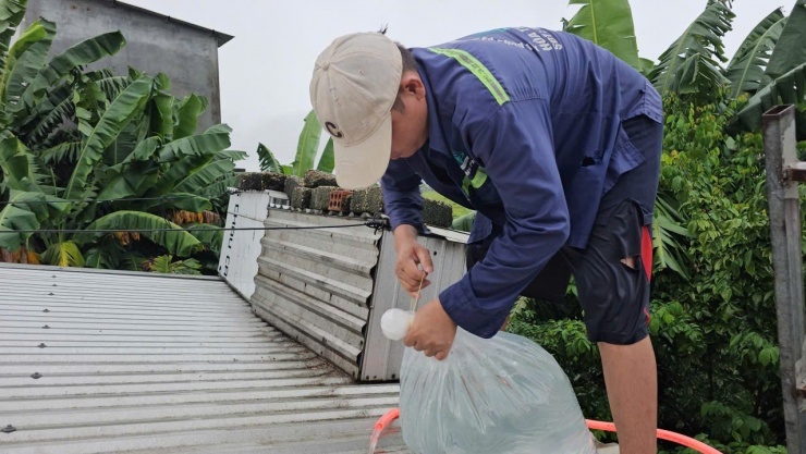 Người dân đưa nước lên mái nhà, bơm vào túi nhựa để làm vật giằng giữ bảo vệ tấm lợp.