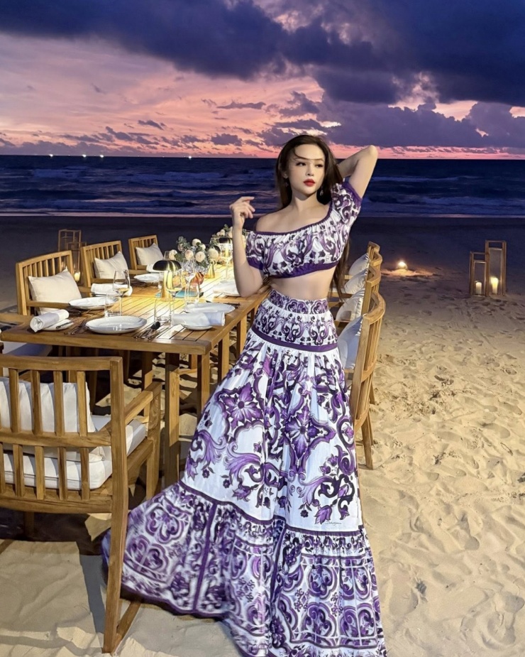 Khoe ảnh trên biển lúc hoàng hôn, Huyền Baby diện set trang phục gồm áo crop top trễ vai và chân váy maxi. Thiết kế mang họa tiết Majolica nằm trong BST mới nhất của Dolce & Gabbana, giá bán khoảng hơn 60 triệu đồng cả set.