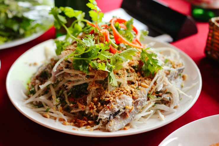 Khi thưởng thức, thực khách lấy bánh tráng, lần lượt xếp các loại rau sống lên trên, thêm miếng gỏi cá trích đã thấm đều gia vị rồi cuốn gỏi lại, quệt với nước chấm đặc sánh, dậy mùi thơm. Ảnh: Nguyễn Thanh Huyền