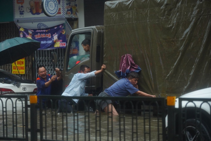 Xe "chết đuối" lao vào biển nước, nhiều người cố gắng đẩy phương tiện ra khỏi khu vực ngập úng.