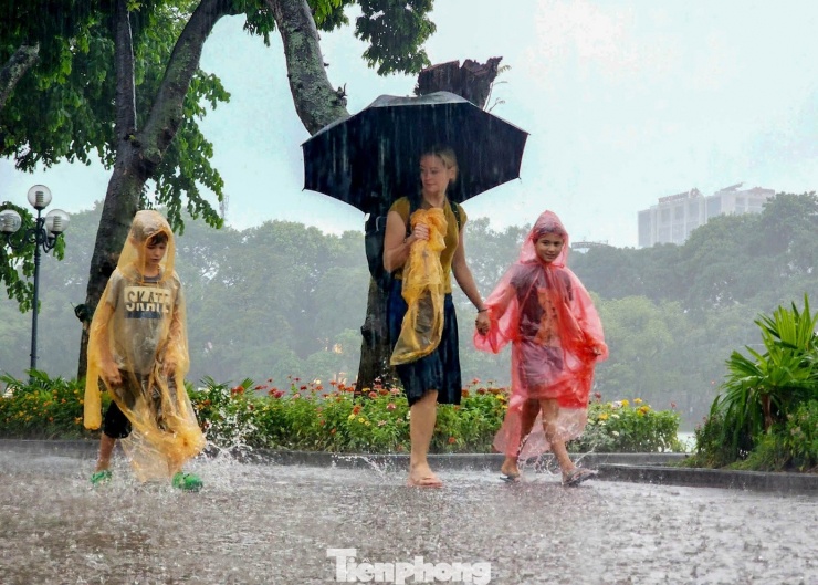 Trái ngược với cảnh người dân vất vả vì ngập úng, khu vực Hồ Gươm vẫn thu hút đông du khách. Nhiều người lội nước trên phố, tranh thủ ghi lại khoảnh khắc hiếm gặp giữa mưa lớn. "Đây là trải nghiệm khác lạ, nên tôi đưa con đi dạo dưới mưa", một du khách chia sẻ.