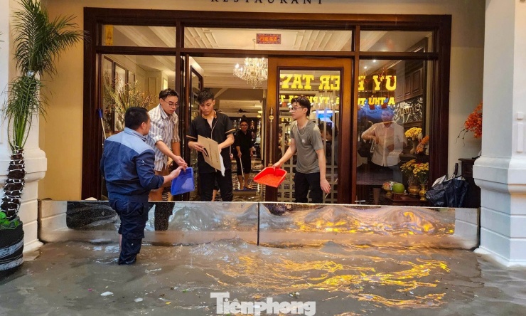 Một khách sạn trên phố Tạ Hiện phải dựng tấm ván chắn nước để ngăn ngập và liên tục tát nước ra ngoài.