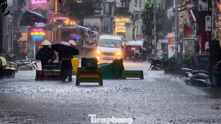 Phía bên ngoài, người dân kê bàn ghế cảnh báo, ngăn các phương tiện đi vào đoạn đường ngập.