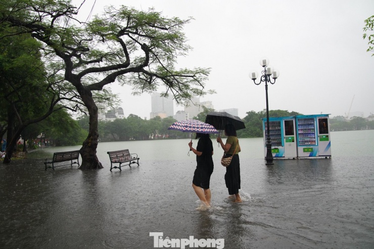 Nước hồ tràn qua đường đi khiến nhiều người dân và du khách ngỡ ngàng vì hiếm khi hồ Gươm xảy ra hiện tượng này