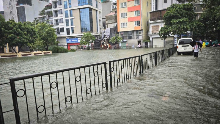 Nước ngập đến nửa bánh xe, các phương tiện di chuyển trên phố Cự Lộc (phường Thanh Xuân) gặp khó khăn. Ghi nhận của PV Tiền Phong tới 16 giờ chiều 30/9, nước trong hồ đã tràn qua mặt đường hơn 20cm.