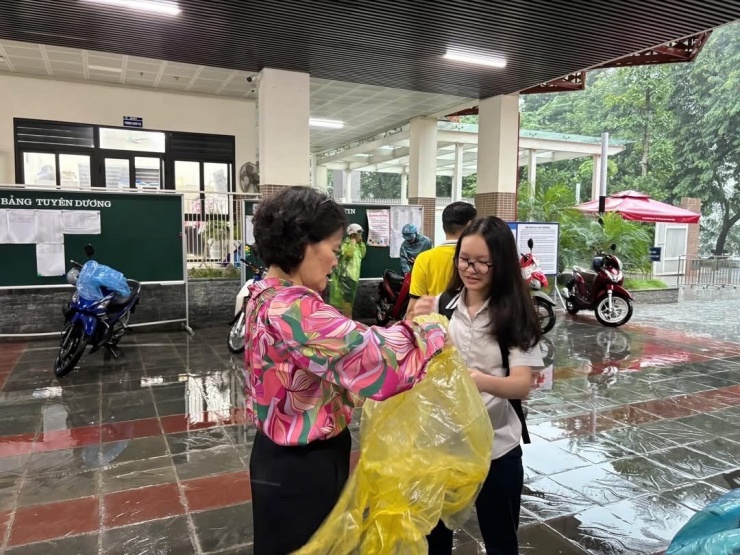 Giáo viên Trường THCS Giảng Võ phát áo mưa cho học sinh được bố mẹ đón về.