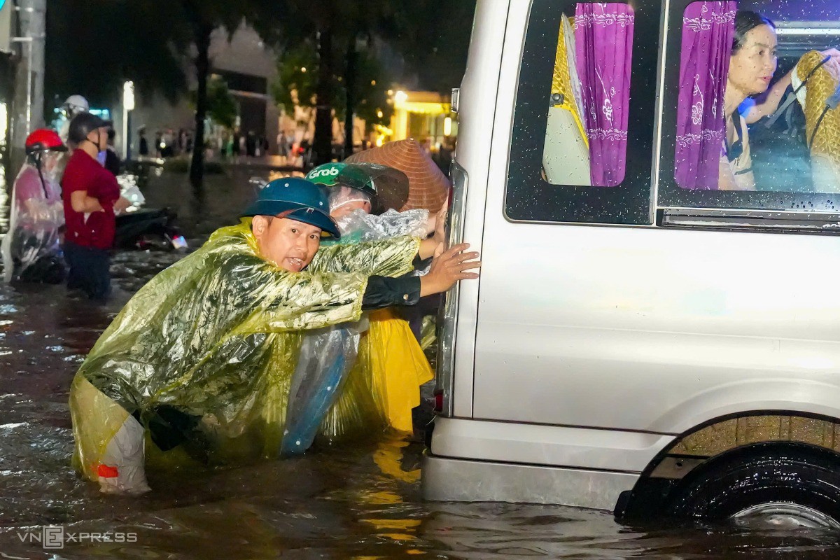 Trong khi đó, nhiều người thuê dịch vụ đẩy xe thoát khỏi chỗ ngập. Ảnh: Tùng Đinh